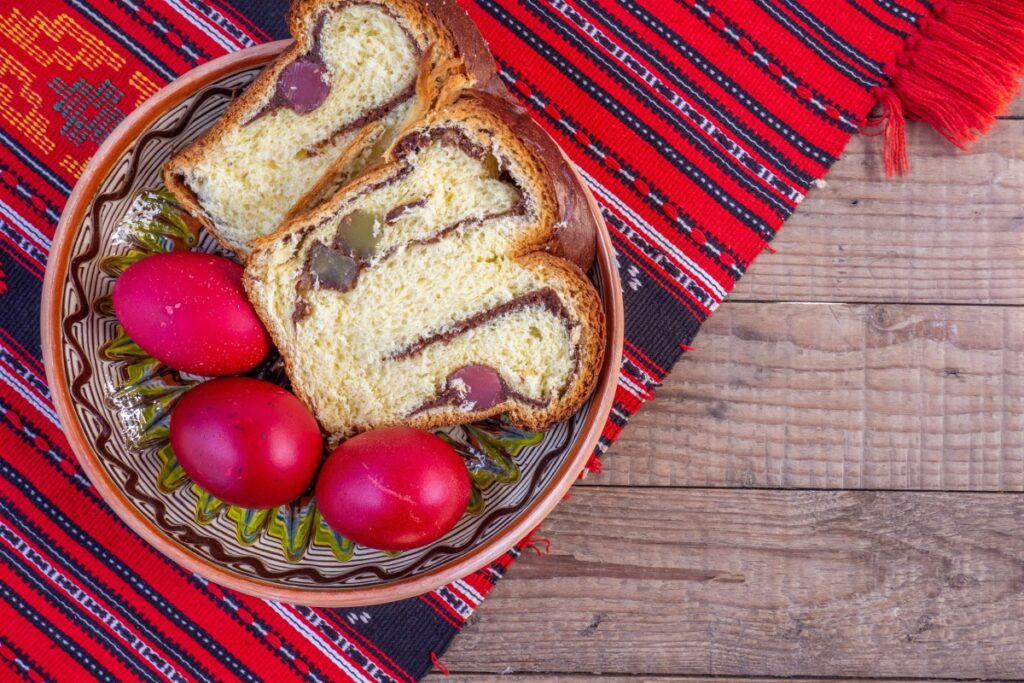 farfurie traditionala cu oua rosii si felii de cozonac de Paste