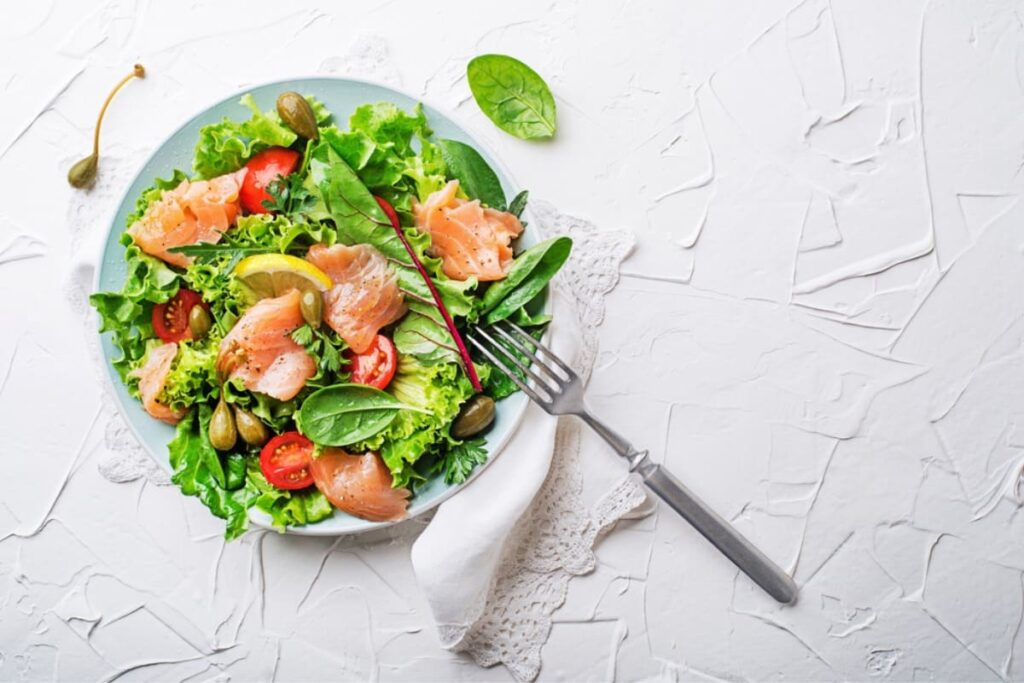 Salata cu somon afumat, rosii cherry si capere pe farfurie bleu