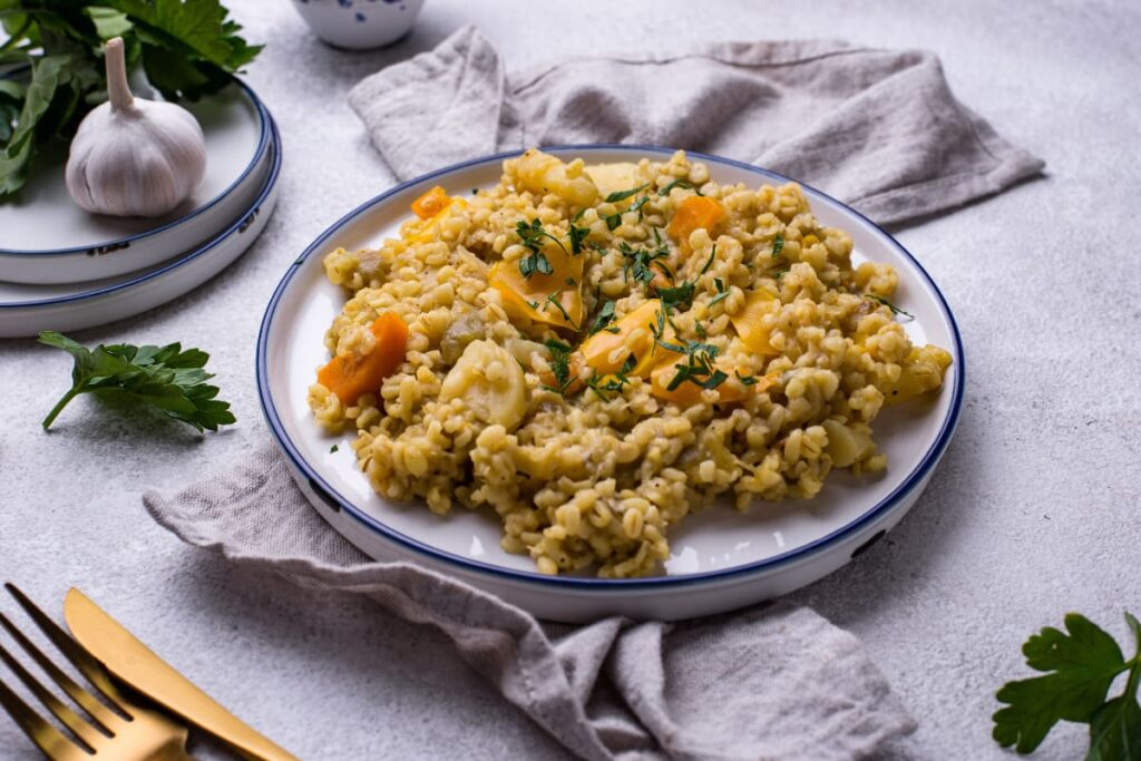 Bulgur cu legume in farfurie alba pe blat din marmura
