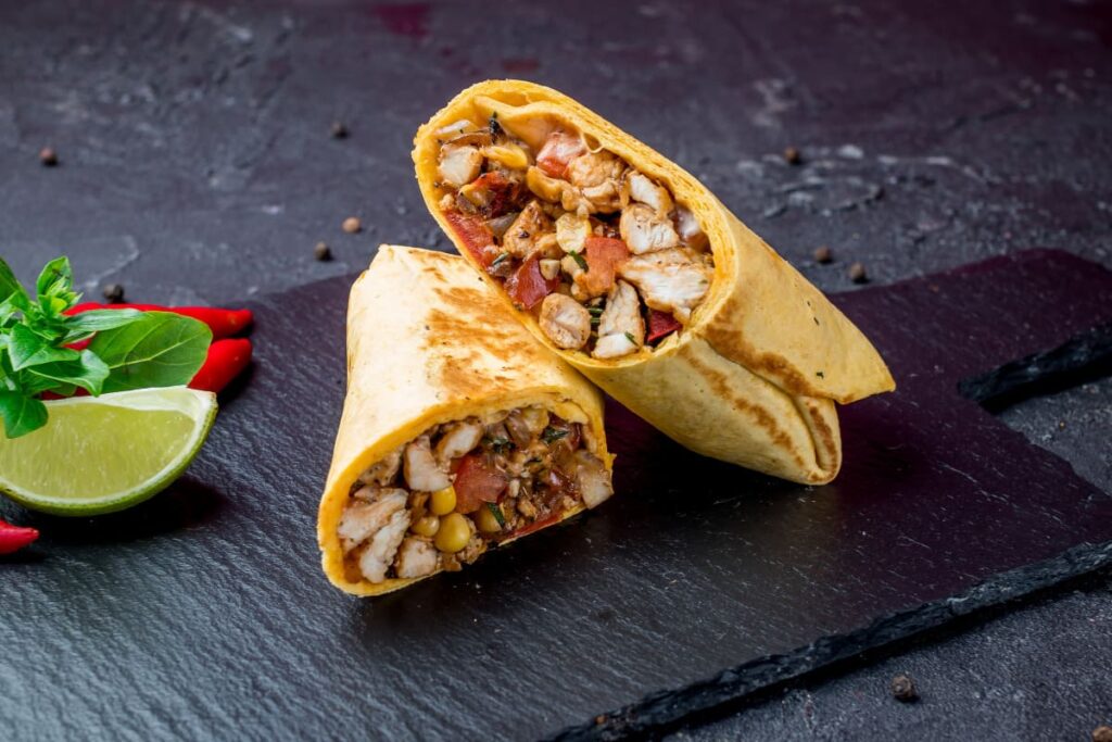 burrito mexican cu carne de pui pe tocator negru din ceramica