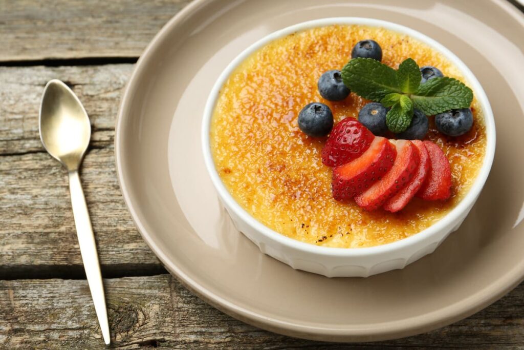 creme brulee in forma ceramica pe farfurie cu afine, capsuni si menta