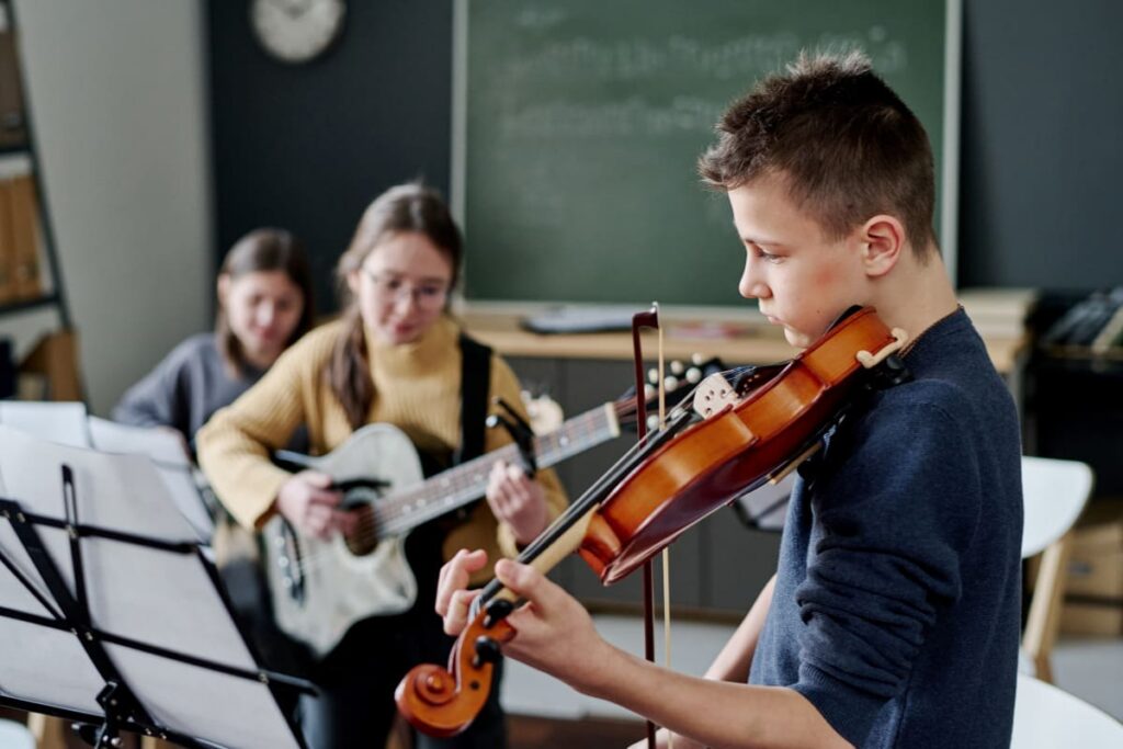 grup de copii care canta la instrumente la atelierul de muzica