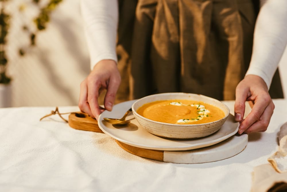 femeier servind supa crema de linte in bol