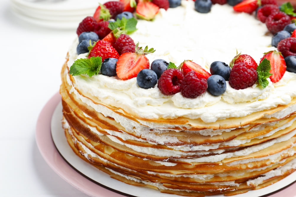 tort de clătite decorat cu zmeură, căpșuni, afine și frunze de mentă