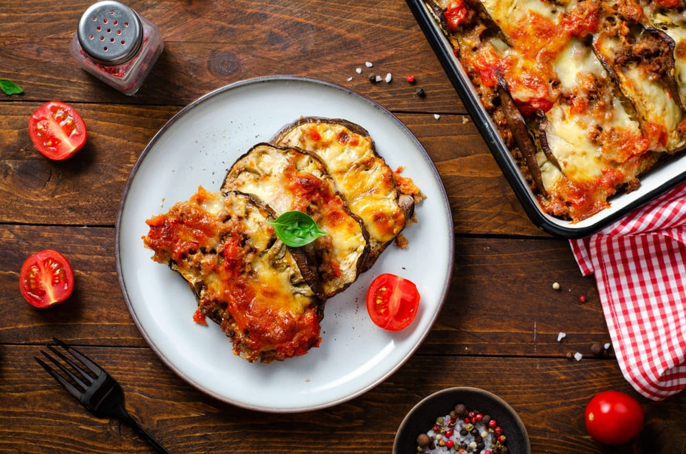 musaca de vinete servita pe farfurie pe masa rustica