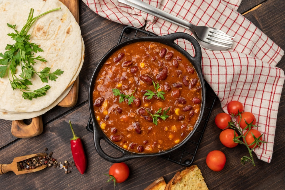 un bol cu chili de post cu fasole servit cu tortilla