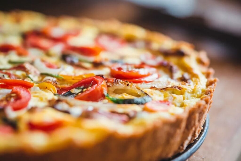 prim-plan cu un quiche cu dovlecel, branz si rosii cherry
